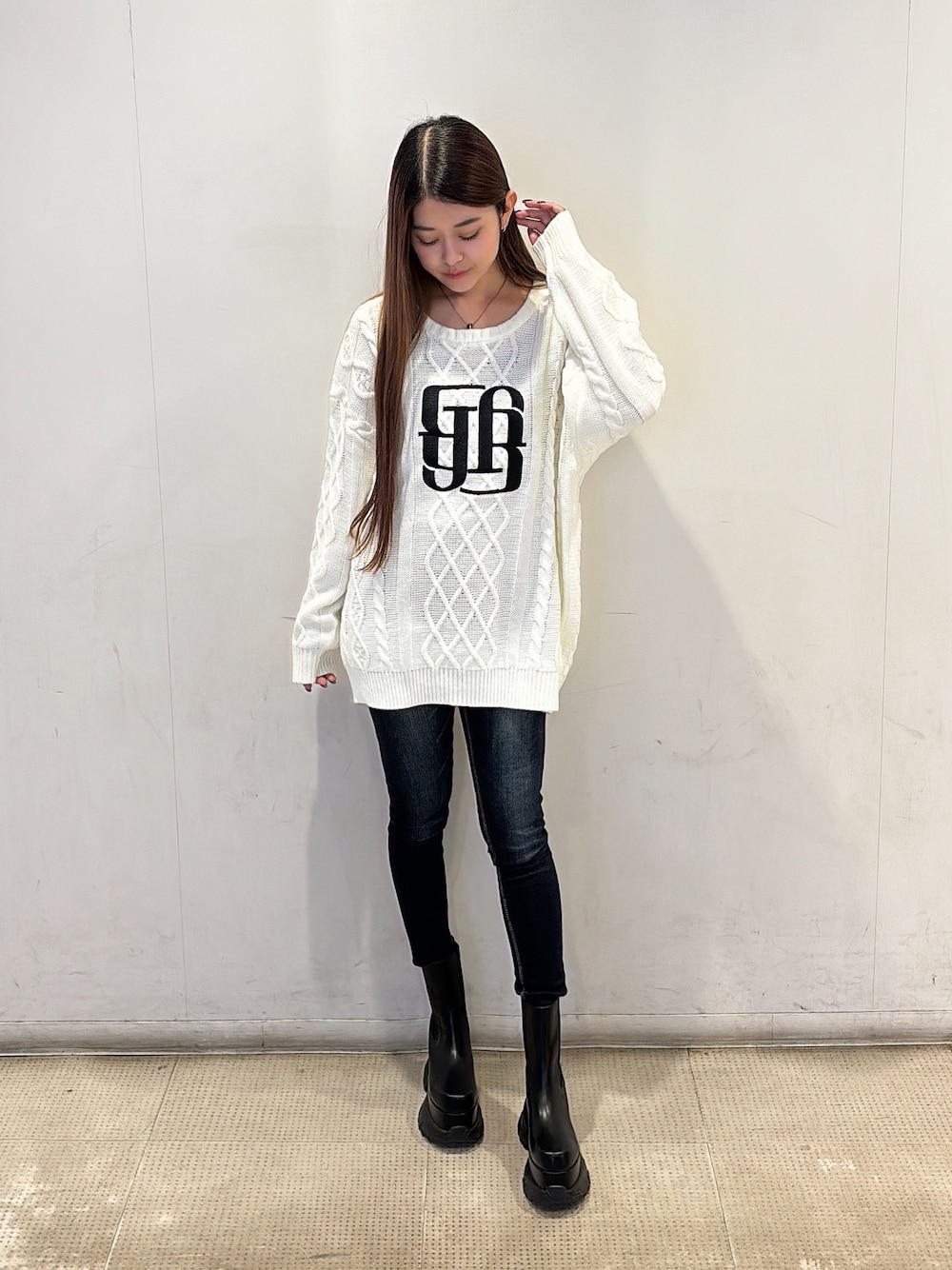 ホワイト系のニット/セーター、ブルー系のデニムパンツ、ブラック系のブーツを着用したレディースの秋コーディネートの1枚目の写真