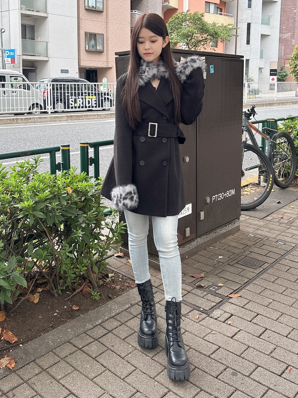 ブラック系のTシャツ/カットソー、ブラック系のチェスターコート、ブルー系のデニムパンツを着用したレディースの秋コーディネートの1枚目の写真