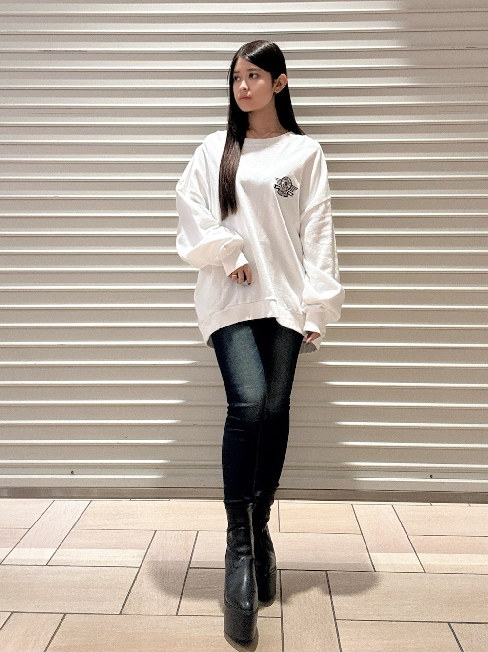 ホワイト系のスウェット、ブルー系のデニムパンツ、ブラック系のブーツを着用したレディースの秋コーディネートの1枚目の写真