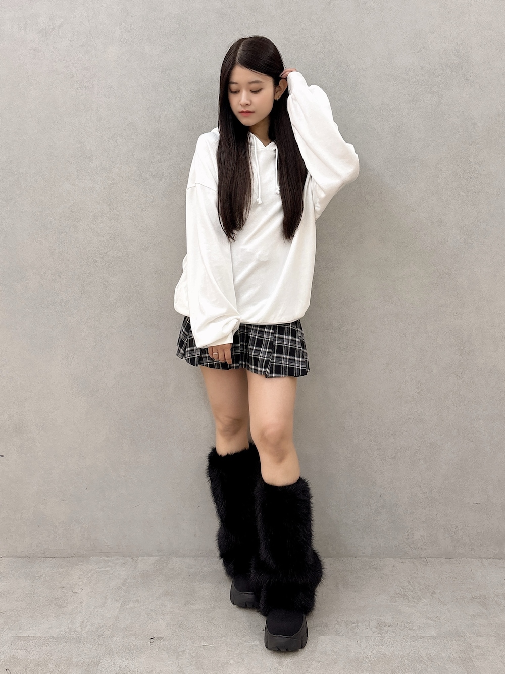 ホワイト系のパーカー、ブラック系のスカート、ブラック系のブーツを着用したレディースの秋コーディネートの1枚目の写真