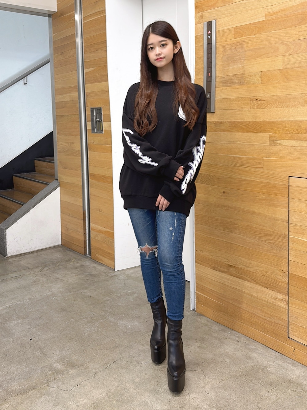 ブラック系のスウェット、ブルー系のデニムパンツ、ブラック系のブーツを着用したレディースの夏コーディネートの1枚目の写真