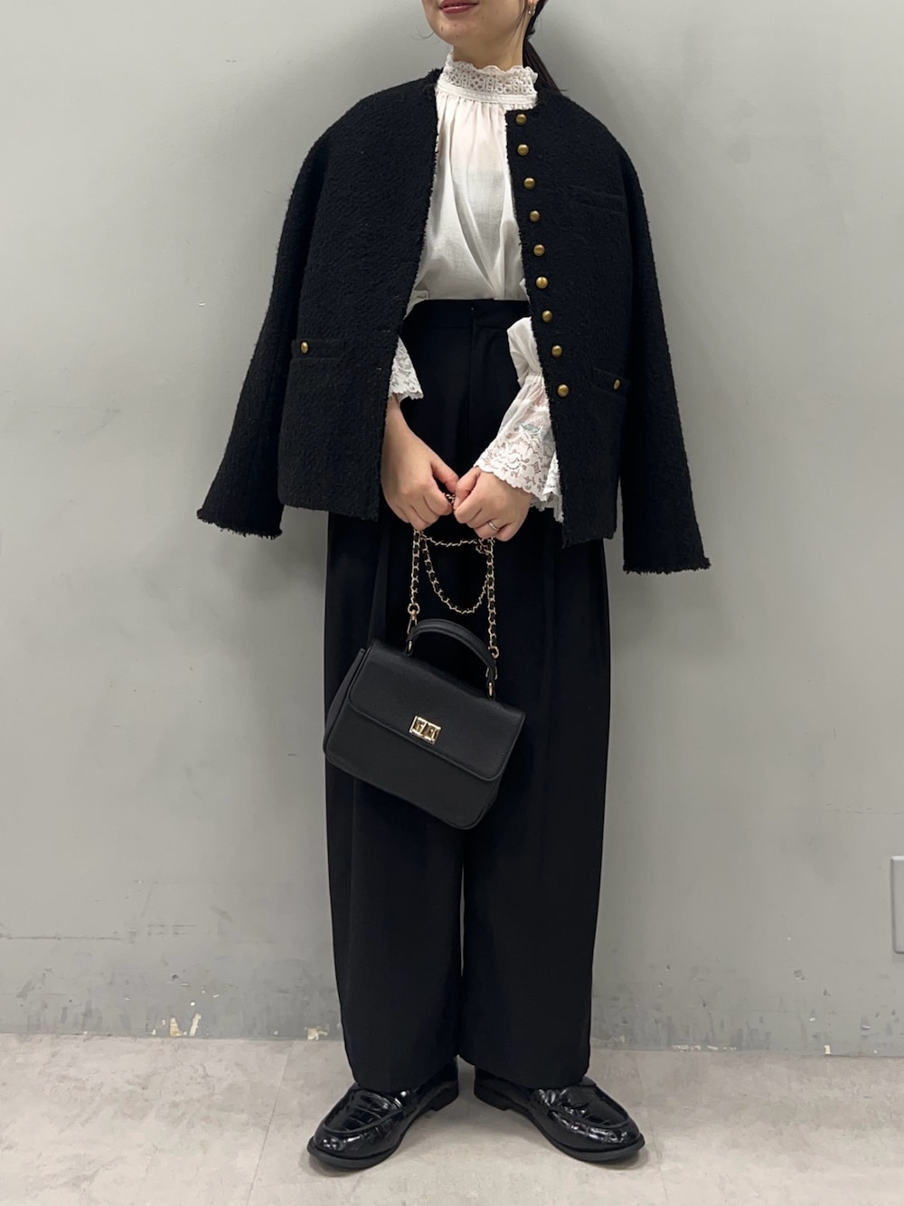 ブラック系のショルダーバッグ、ブラック系のスラックス、ブラック系のノーカラージャケットを着用したレディースの冬コーディネートの1枚目の写真