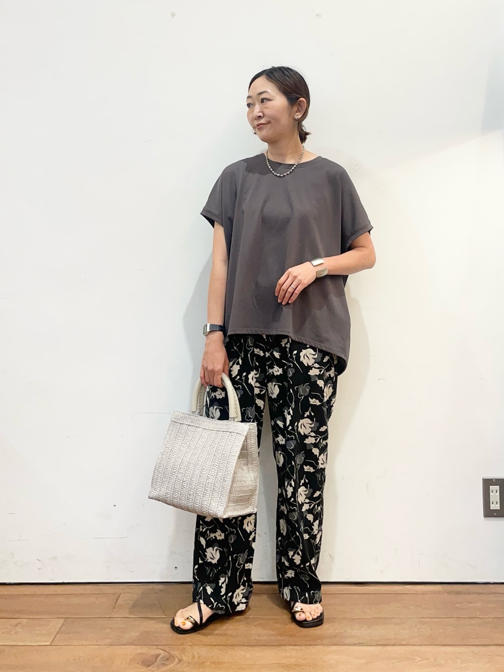 グレー系のTシャツ/カットソー、グレー系のハンドバッグ、ブラック系のサンダルを着用したレディースの夏コーディネートの1枚目の写真