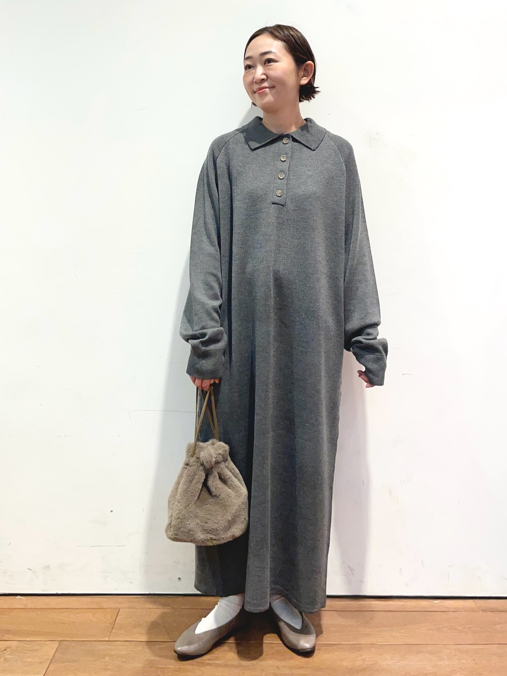 グレー系のワンピース、ブラウン系のショルダーバッグ、ベージュ系のパンプスを着用したレディースの秋コーディネートの1枚目の写真