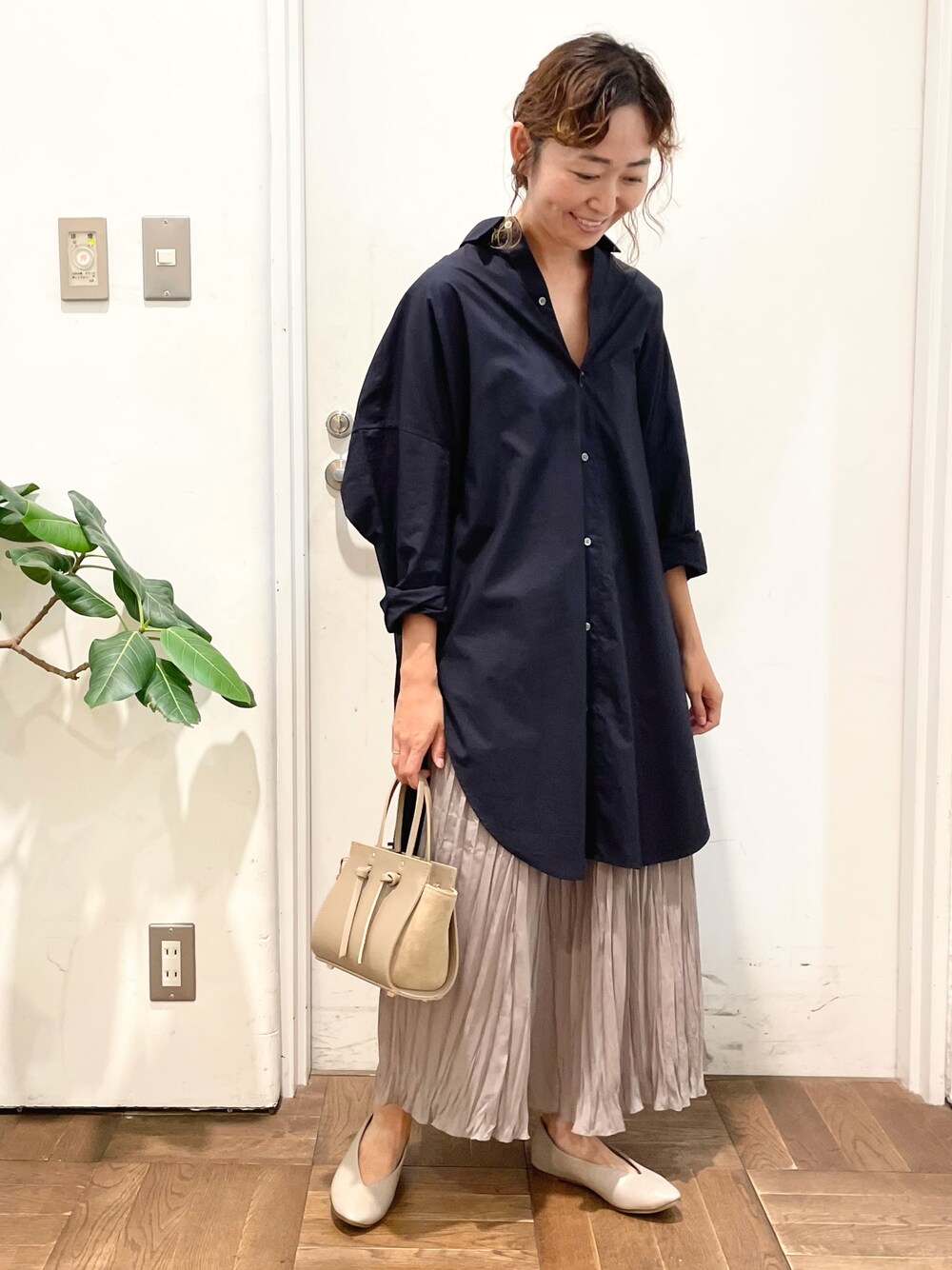 ブルー系のシャツ/ブラウス、グレー系のスカート、ベージュ系のハンドバッグを着用したレディースの夏コーディネートの1枚目の写真