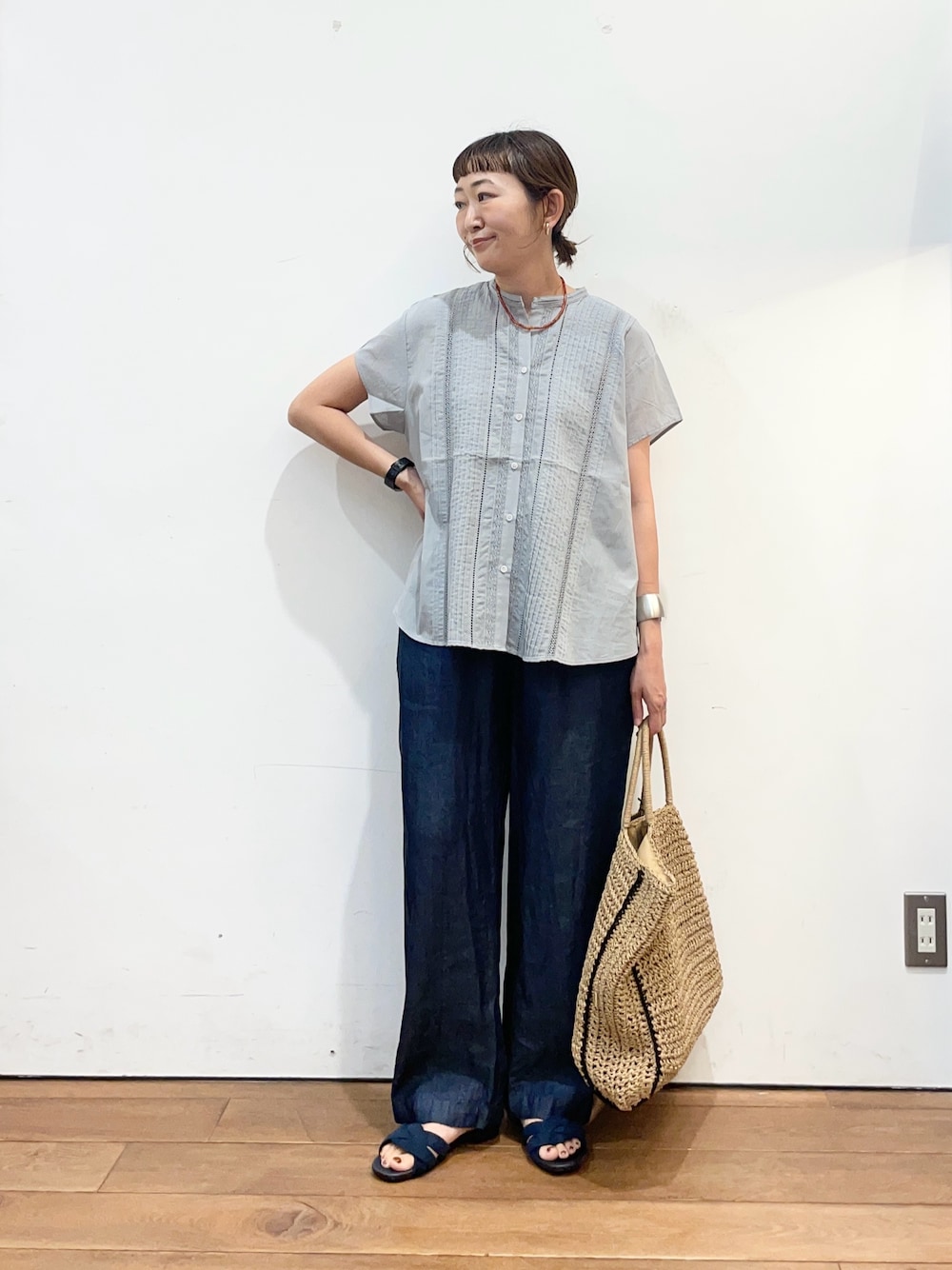 グレー系のシャツ/ブラウス、ブルー系のデニムパンツ、ベージュ系のトートバッグを着用したレディースの夏コーディネートの1枚目の写真