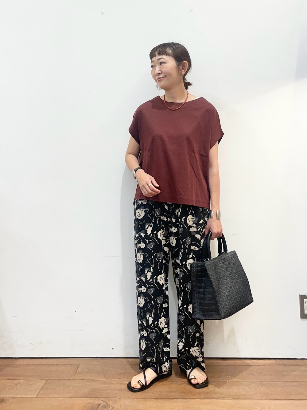 レッド系のTシャツ/カットソー、ブラック系のサンダル、ブラック系のハンドバッグを着用したレディースの夏コーディネートの1枚目の写真