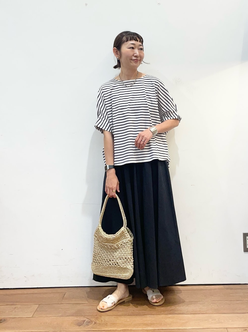 ホワイト系のTシャツ/カットソー、ブラック系のスカート、ホワイト系のサンダルを着用したレディースの夏コーディネートの1枚目の写真