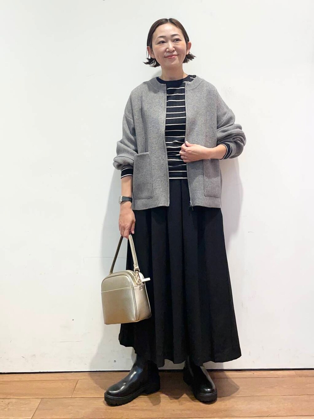 ブラック系のTシャツ/カットソー、ゴールド系のショルダーバッグ、ブラック系のブーツを着用したレディースの秋コーディネートの1枚目の写真