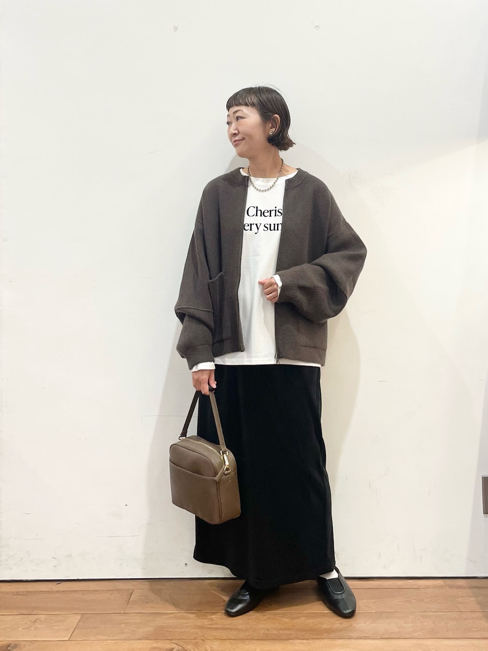 ブラウン系のブルゾン、ホワイト系のTシャツ/カットソー、ブラウン系のショルダーバッグを着用したレディースの秋コーディネートの1枚目の写真