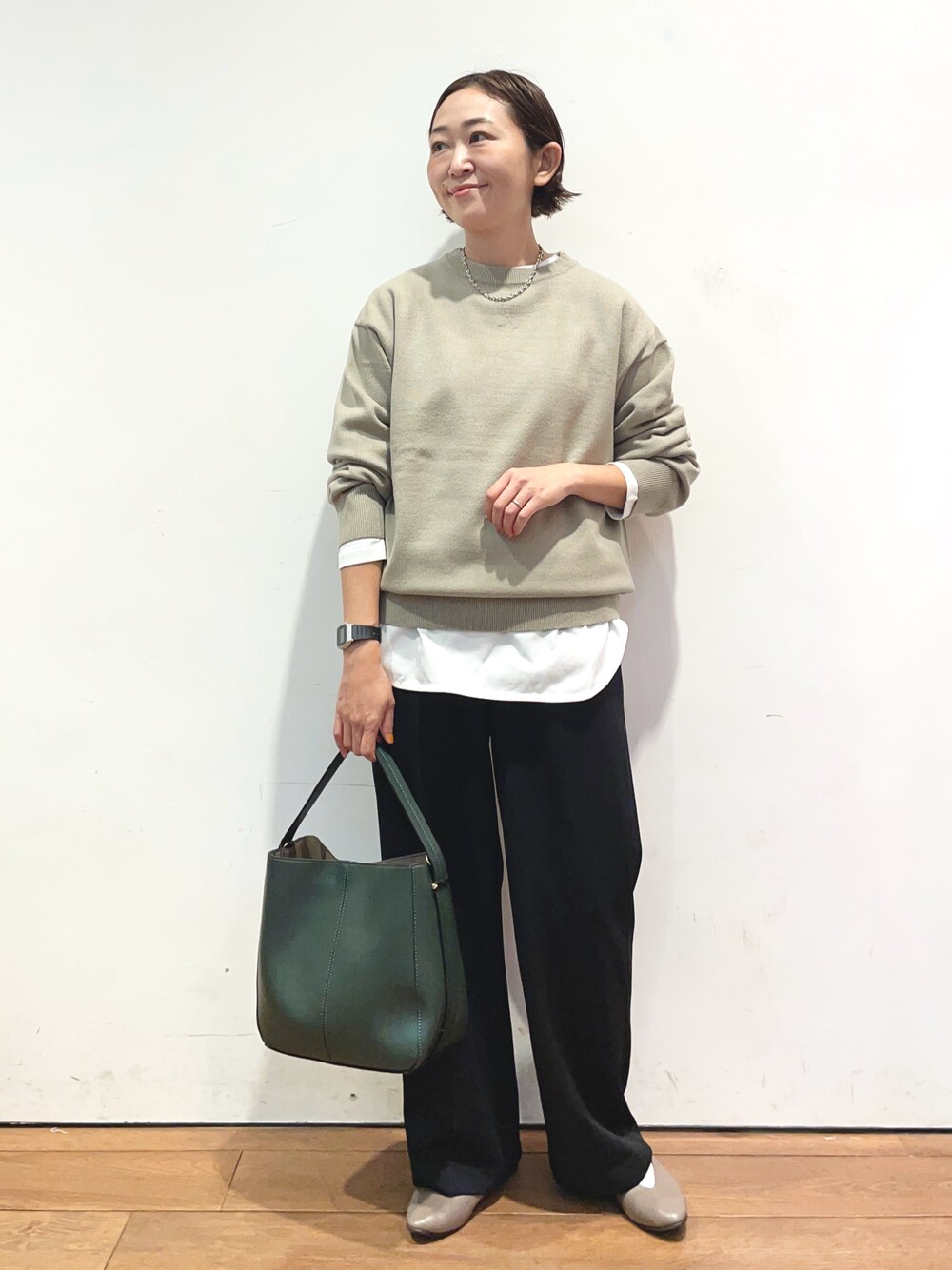 ベージュ系のニット/セーター、ホワイト系のTシャツ/カットソー、グリーン系のハンドバッグを着用したレディースの秋コーディネートの1枚目の写真