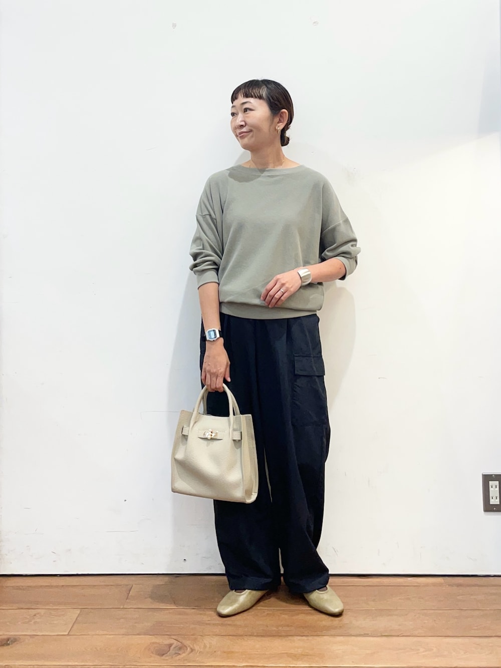 グリーン系のTシャツ/カットソー、グレー系のハンドバッグ、ブラウン系のスリッポンを着用したレディースの秋コーディネートの1枚目の写真
