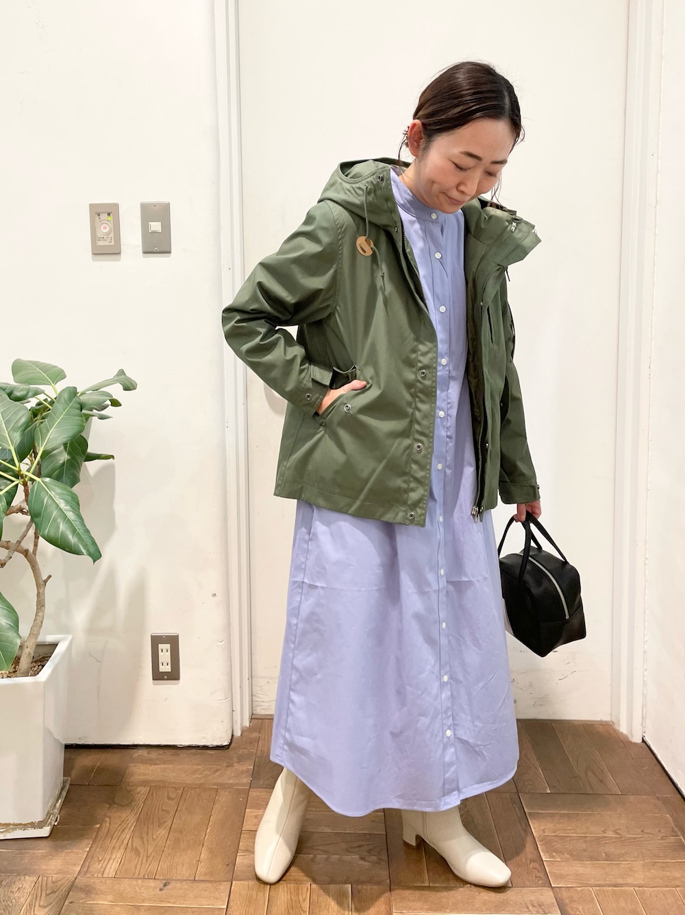 グリーン系のマウンテンパーカー、ブルー系のワンピース、ホワイト系のブーツを着用したレディースの冬コーディネートの1枚目の写真