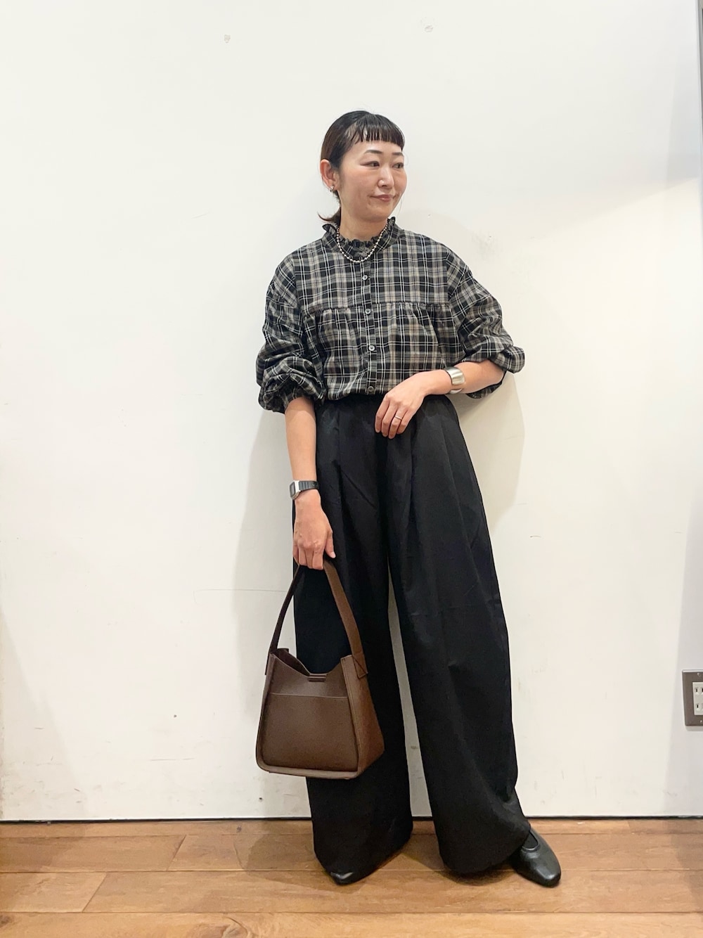 ブラック系のシャツ/ブラウス、ブラック系のその他パンツ、ブラウン系のハンドバッグを着用したレディースの秋コーディネートの1枚目の写真