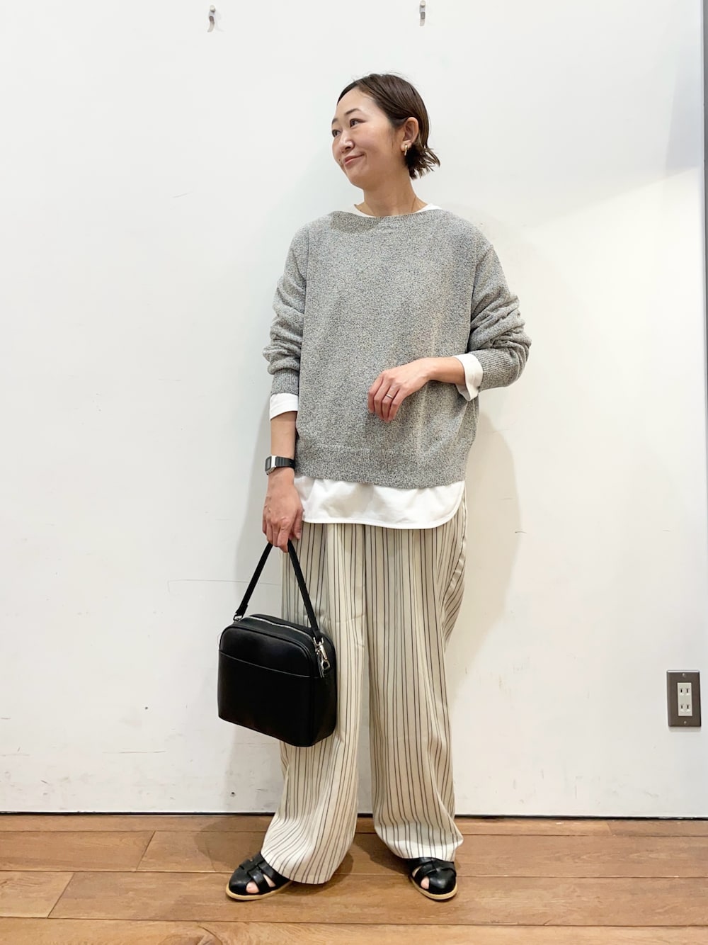 ブラック系のニット/セーター、ホワイト系のTシャツ/カットソー、ベージュ系のその他パンツを着用したレディースの春コーディネートの1枚目の写真