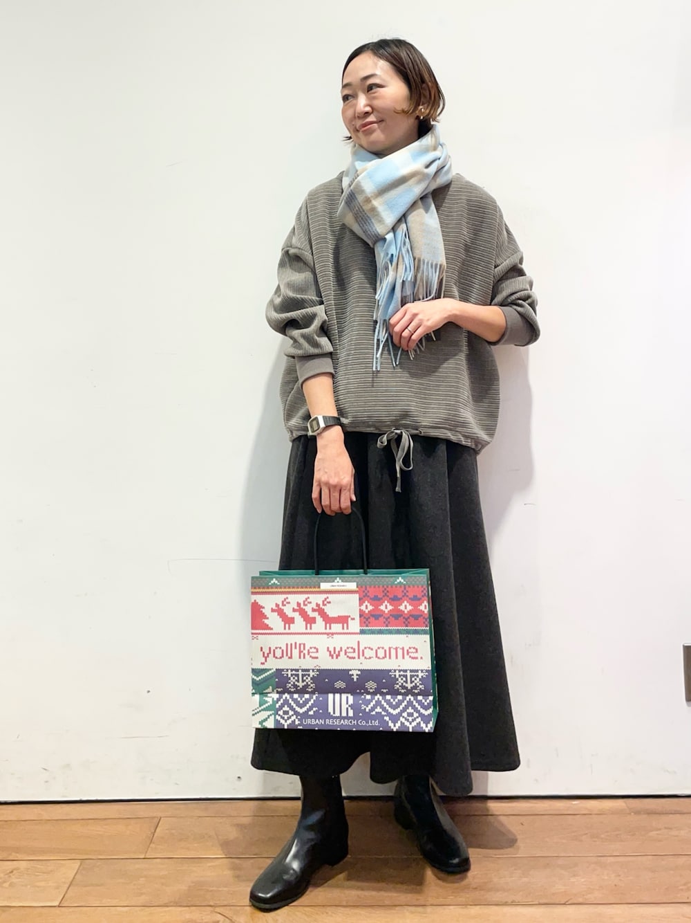 グレー系のスカート、ブラック系のブーツ、グレー系のTシャツ/カットソーを着用したレディースの冬コーディネートの1枚目の写真