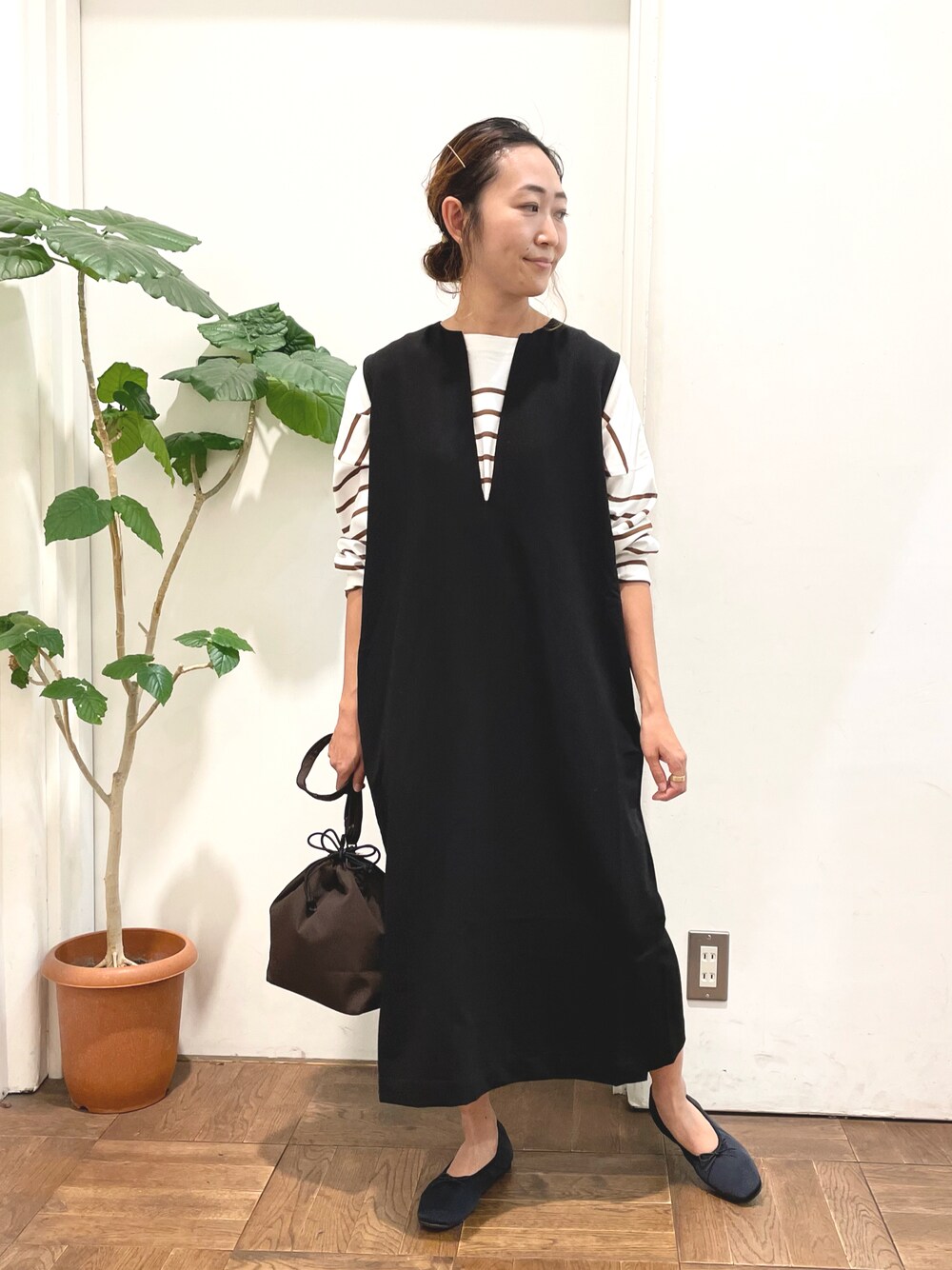 ブラック系のワンピース、ブラウン系のTシャツ/カットソー、ブラウン系のショルダーバッグを着用したレディースの秋コーディネートの1枚目の写真
