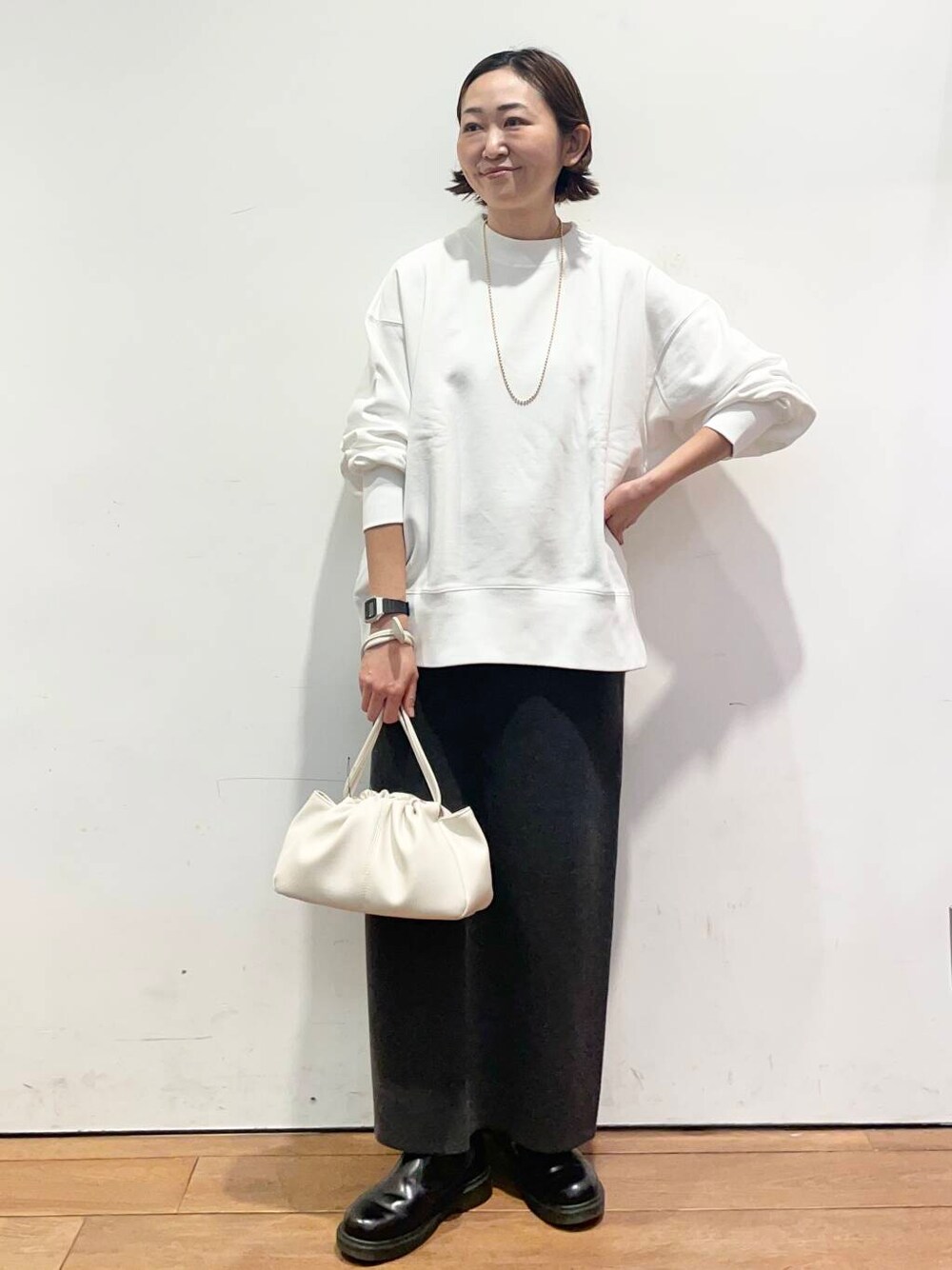 グレー系のスカート、ホワイト系のショルダーバッグ、ホワイト系のTシャツ/カットソーを着用したレディースの冬コーディネートの1枚目の写真