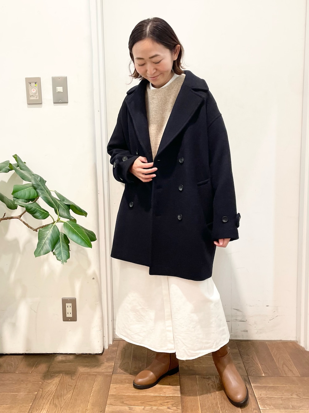 ベージュ系のニット/セーター、ホワイト系のワンピース、ブラウン系のブーツを着用したレディースの冬コーディネートの1枚目の写真