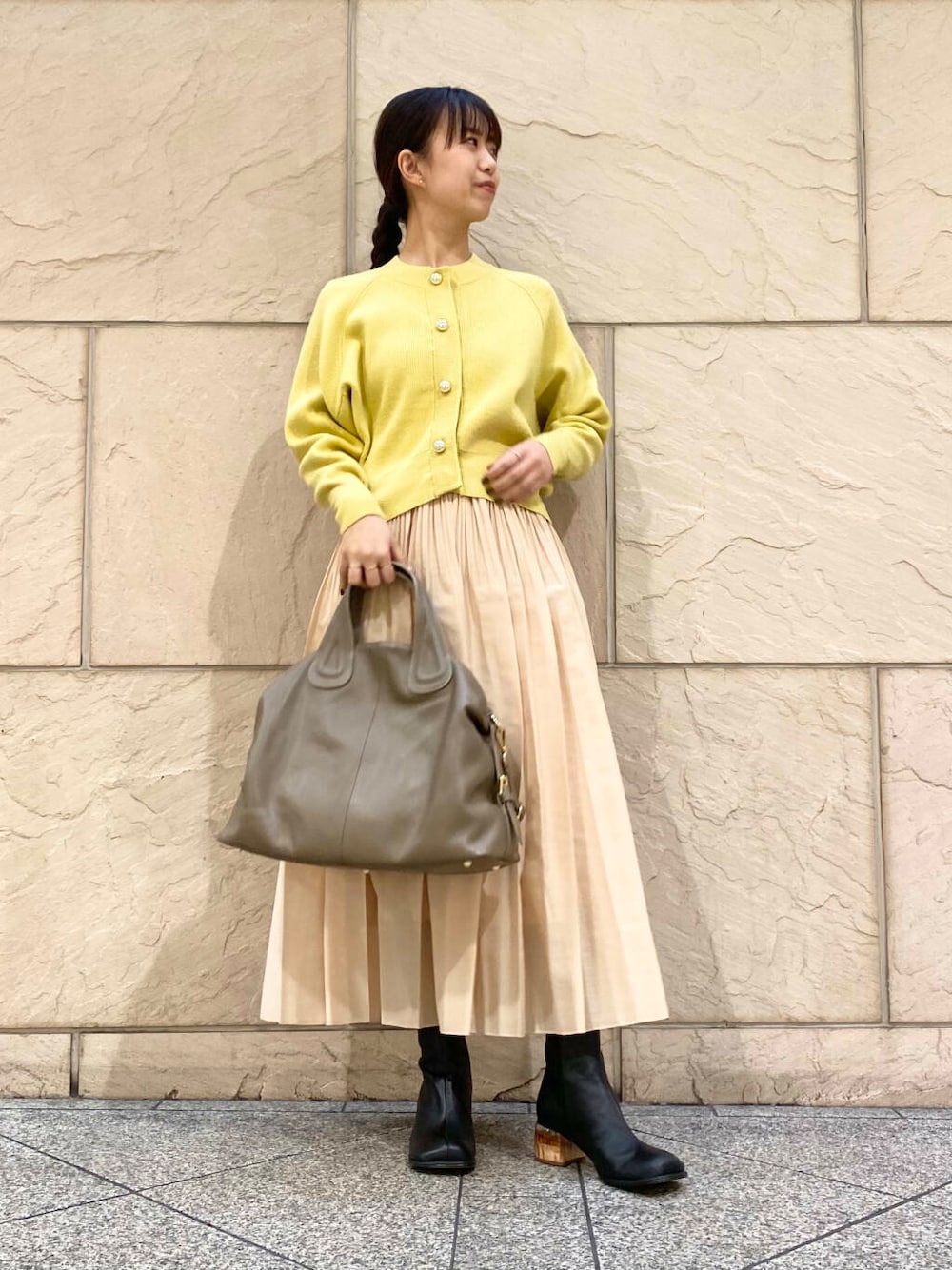 ベージュ系のボストンバッグ、イエロー系のスカート、イエロー系のカーディガン/ボレロを着用したレディースの冬コーディネートの1枚目の写真