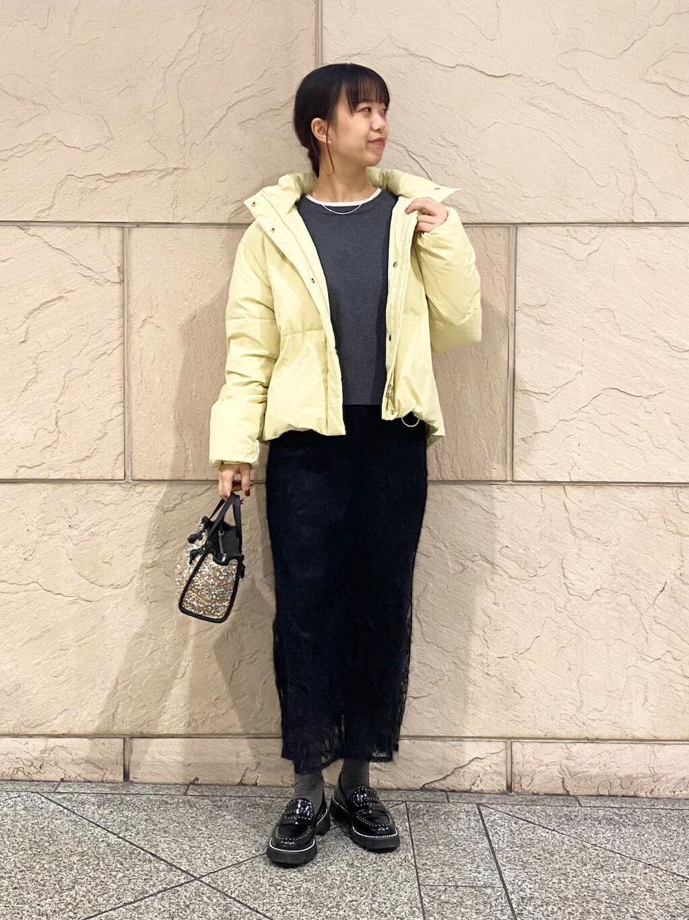 イエロー系のダウンジャケット/コート、グレー系のニット/セーター、イエロー系のハンドバッグを着用したレディースの冬コーディネートの1枚目の写真