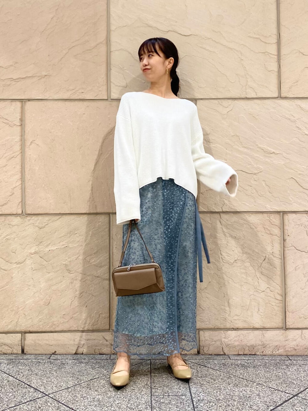 ベージュ系のパンプス、ブルー系のスカート、ホワイト系のニット/セーターを着用したレディースの冬コーディネートの1枚目の写真