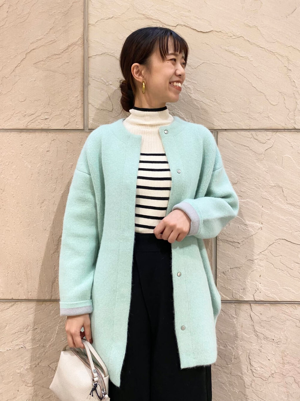 ブラック系のその他パンツ、ホワイト系のニット/セーター、グリーン系のカーディガン/ボレロを着用したレディースの秋コーディネートの1枚目の写真