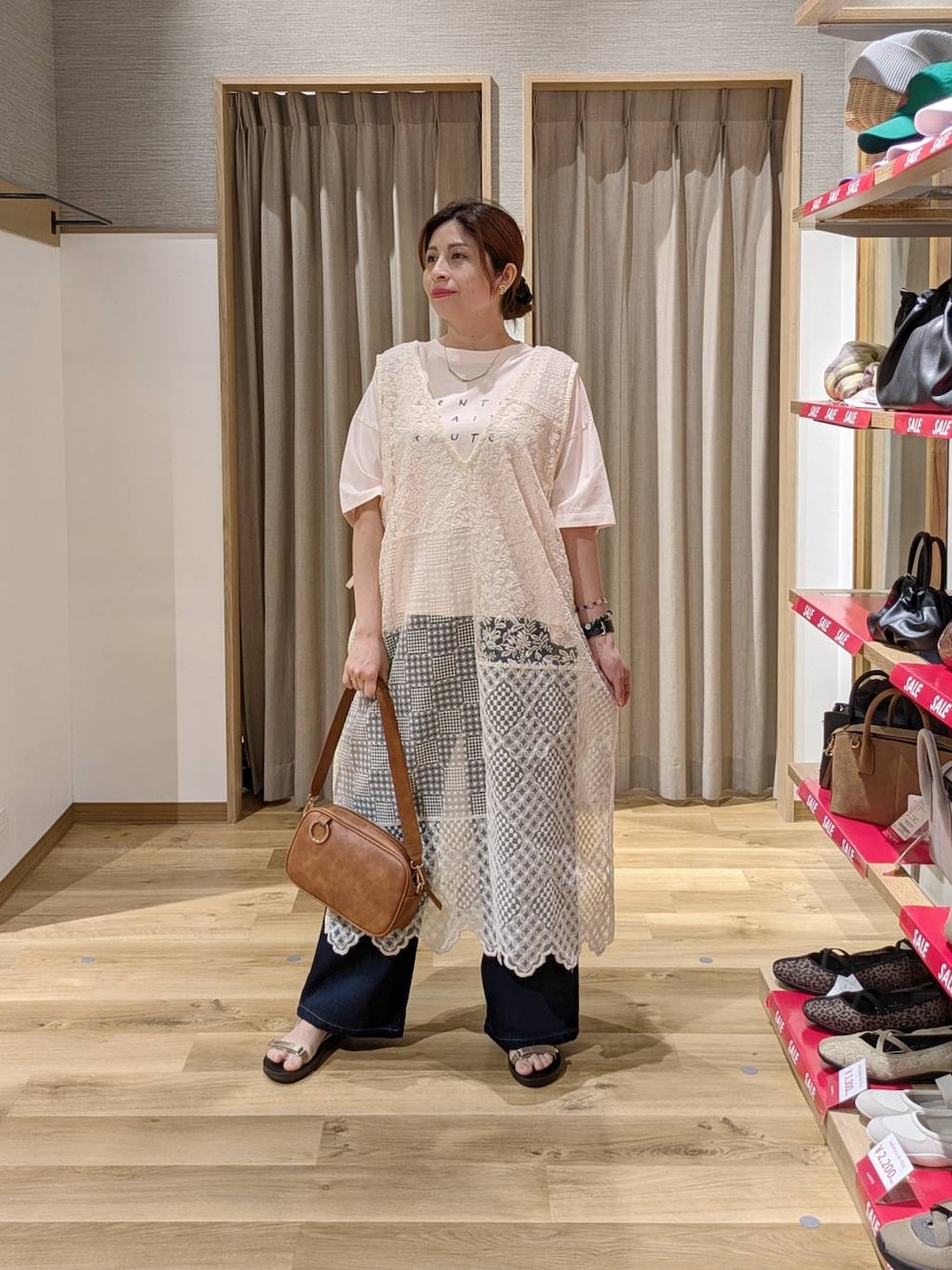 ブラウン系のショルダーバッグ、ゴールド系のサンダル、ブルー系のデニムパンツを着用したレディースの夏コーディネートの1枚目の写真