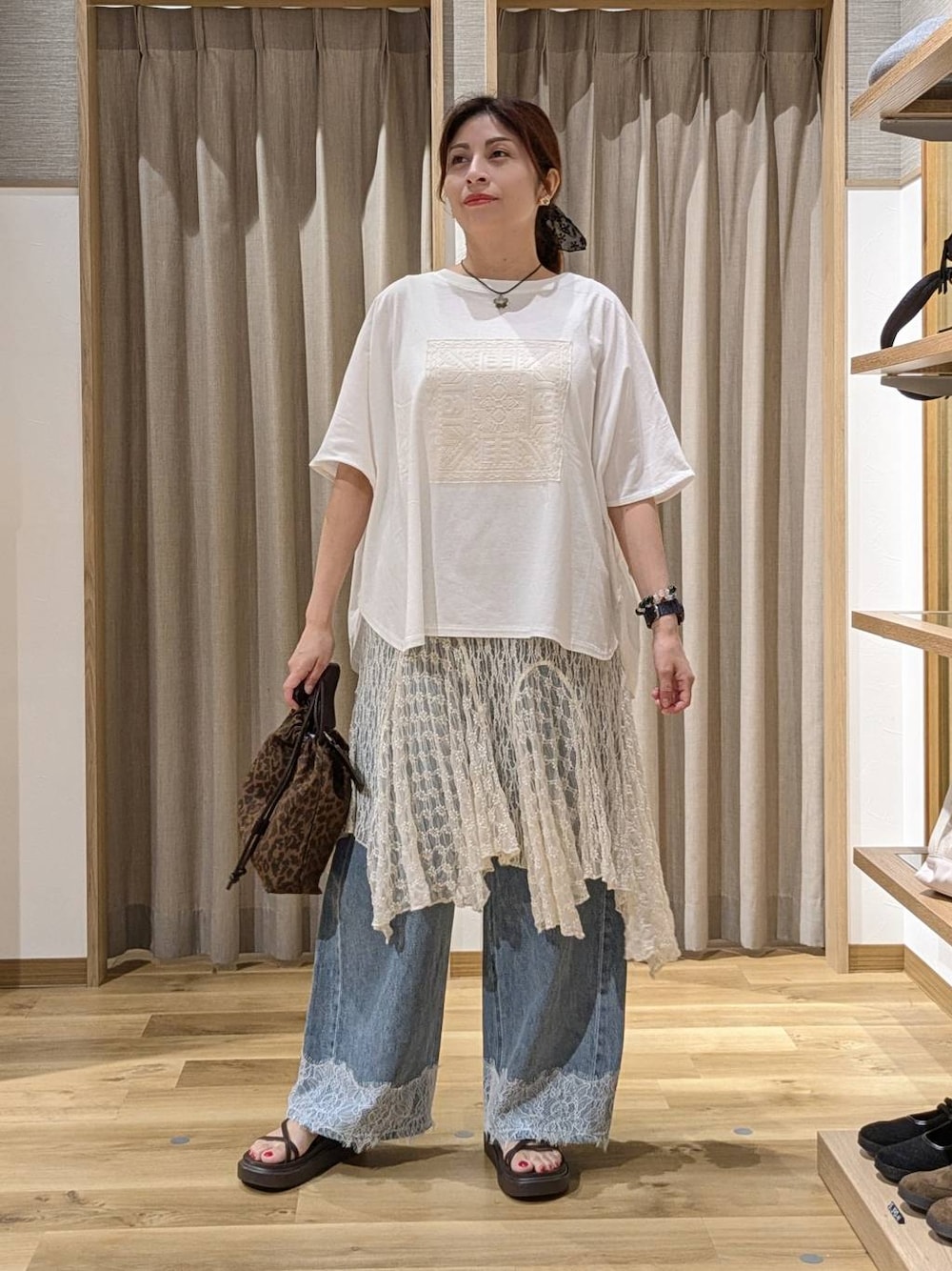 ブルー系のデニムパンツ、ブラウン系のショルダーバッグ、ブラウン系のサンダルを着用したレディースの夏コーディネートの1枚目の写真