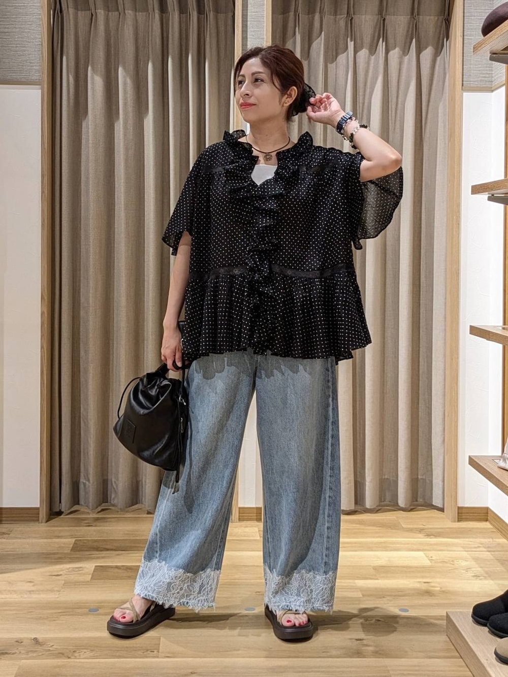 ブルー系のデニムパンツ、ベージュ系のサンダル、ブラック系のトートバッグを着用したレディースの夏コーディネートの1枚目の写真