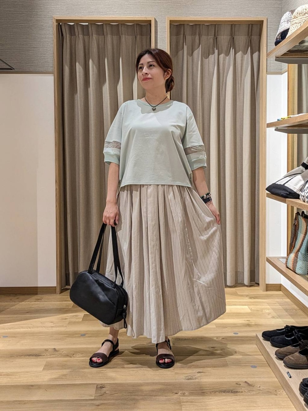 ブラック系のショルダーバッグ、グリーン系のTシャツ/カットソー、その他のスカートを着用したレディースの夏コーディネートの1枚目の写真