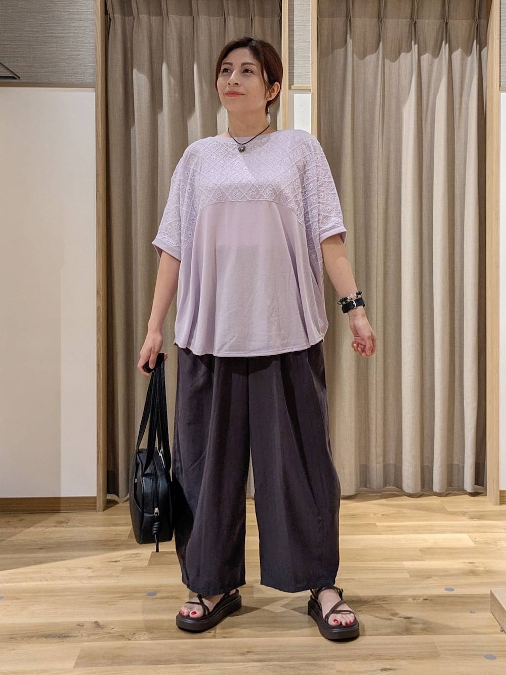 ブラック系のショルダーバッグ、パープル系のTシャツ/カットソー、ブラウン系のサンダルを着用したレディースの夏コーディネートの1枚目の写真