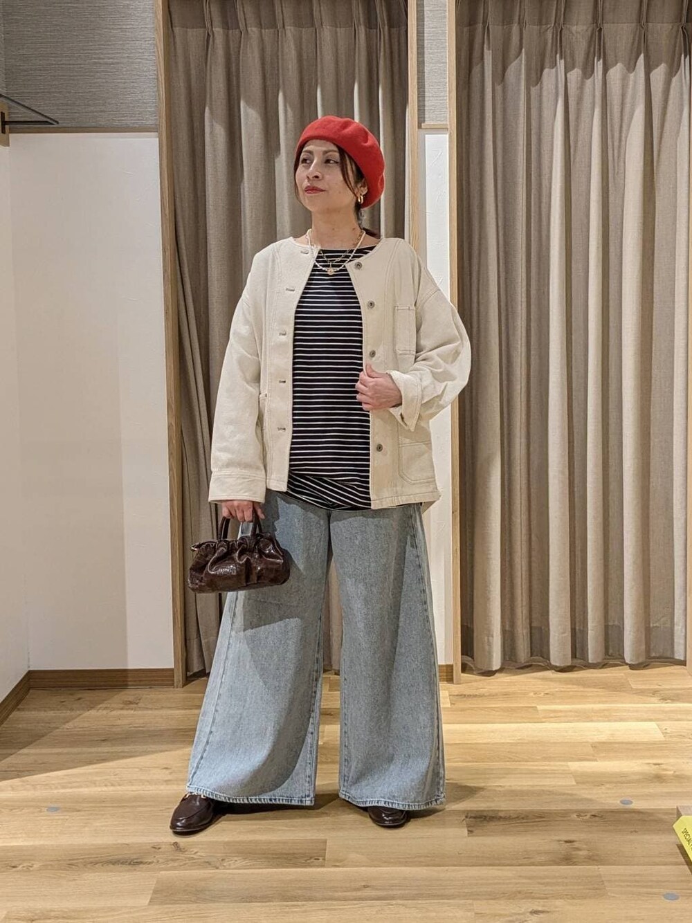 ブルー系のデニムパンツ、ベージュ系のノーカラージャケット、ブラウン系のショルダーバッグを着用したレディースの冬コーディネートの1枚目の写真