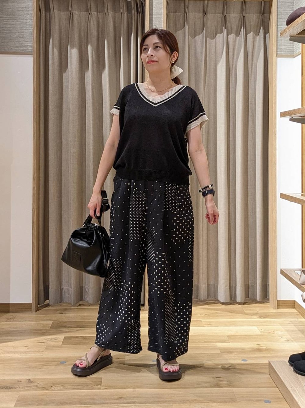 ブラック系のニット/セーター、ベージュ系のサンダル、ブラック系のトートバッグを着用したレディースの夏コーディネートの1枚目の写真