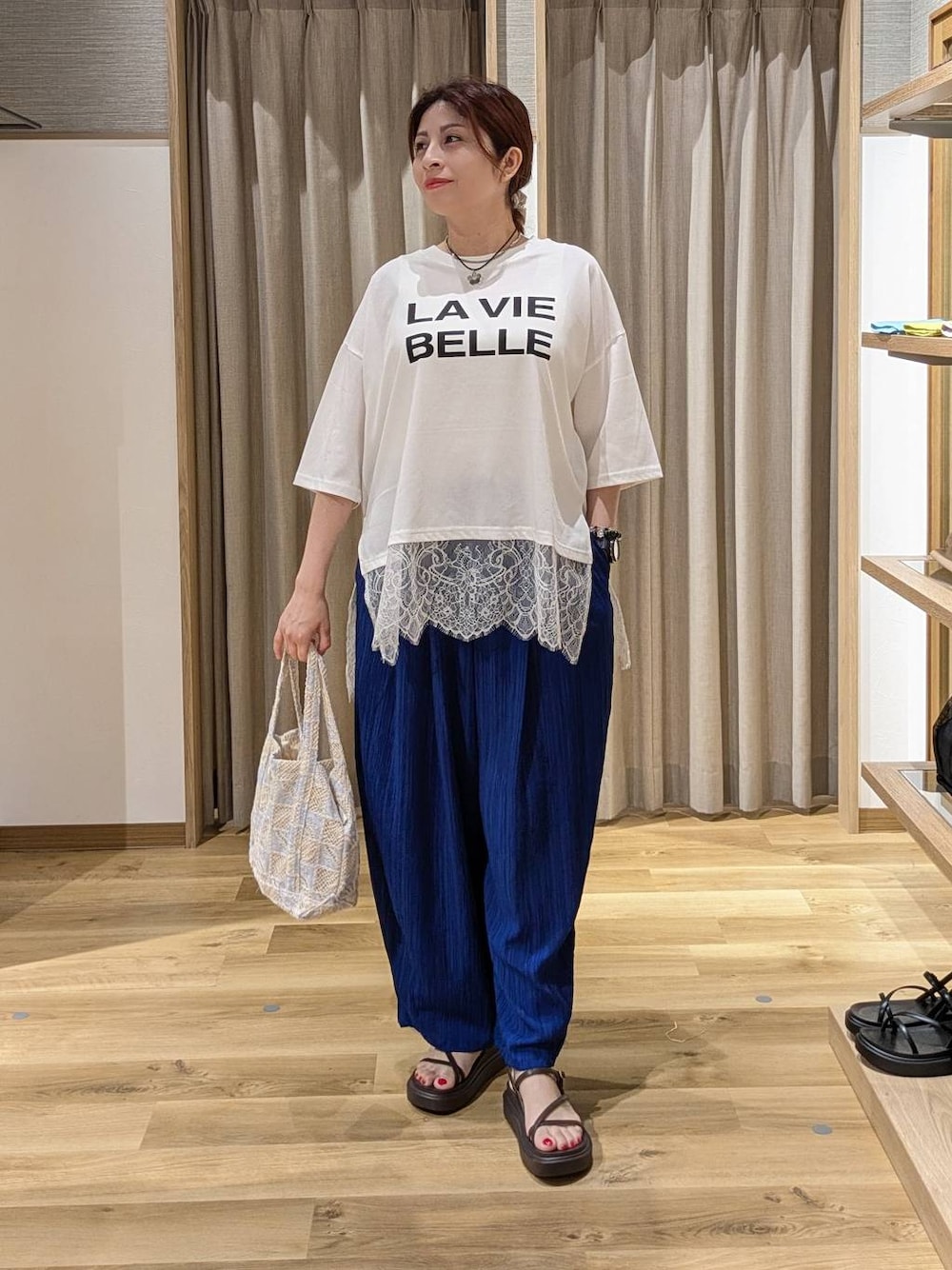 ブルー系のその他パンツ、ブラウン系のサンダル、ブルー系のトートバッグを着用したレディースの夏コーディネートの1枚目の写真