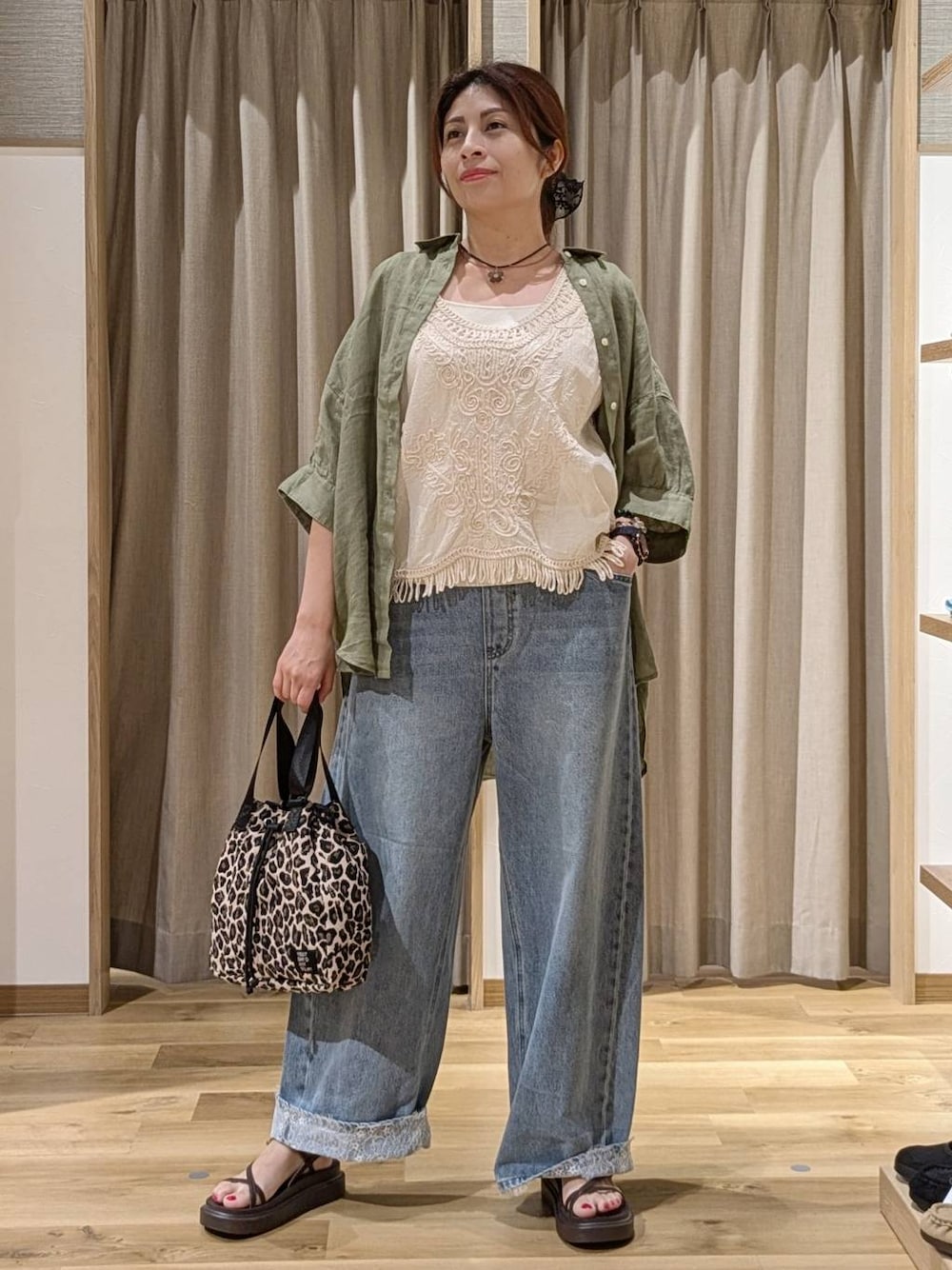 ブルー系のデニムパンツ、ベージュ系のシャツ/ブラウス、ブラウン系のサンダルを着用したレディースの夏コーディネートの1枚目の写真