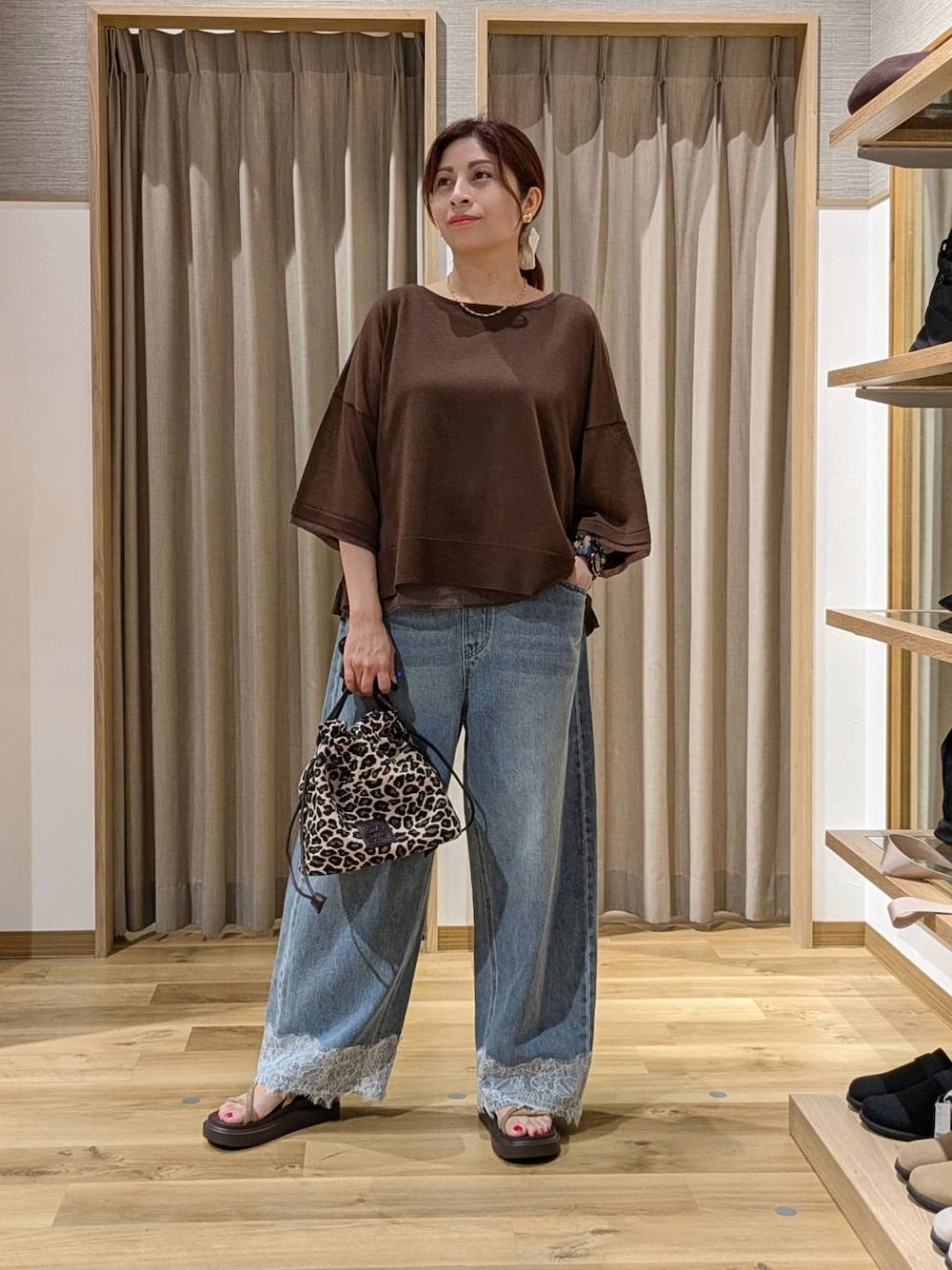 ブルー系のデニムパンツ、ベージュ系のサンダル、ブラウン系のニット/セーターを着用したレディースの夏コーディネートの1枚目の写真