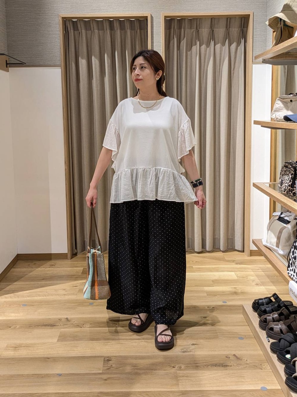 ブラウン系のトートバッグ、ブラウン系のサンダル、ブラック系のその他パンツを着用したレディースの夏コーディネートの1枚目の写真