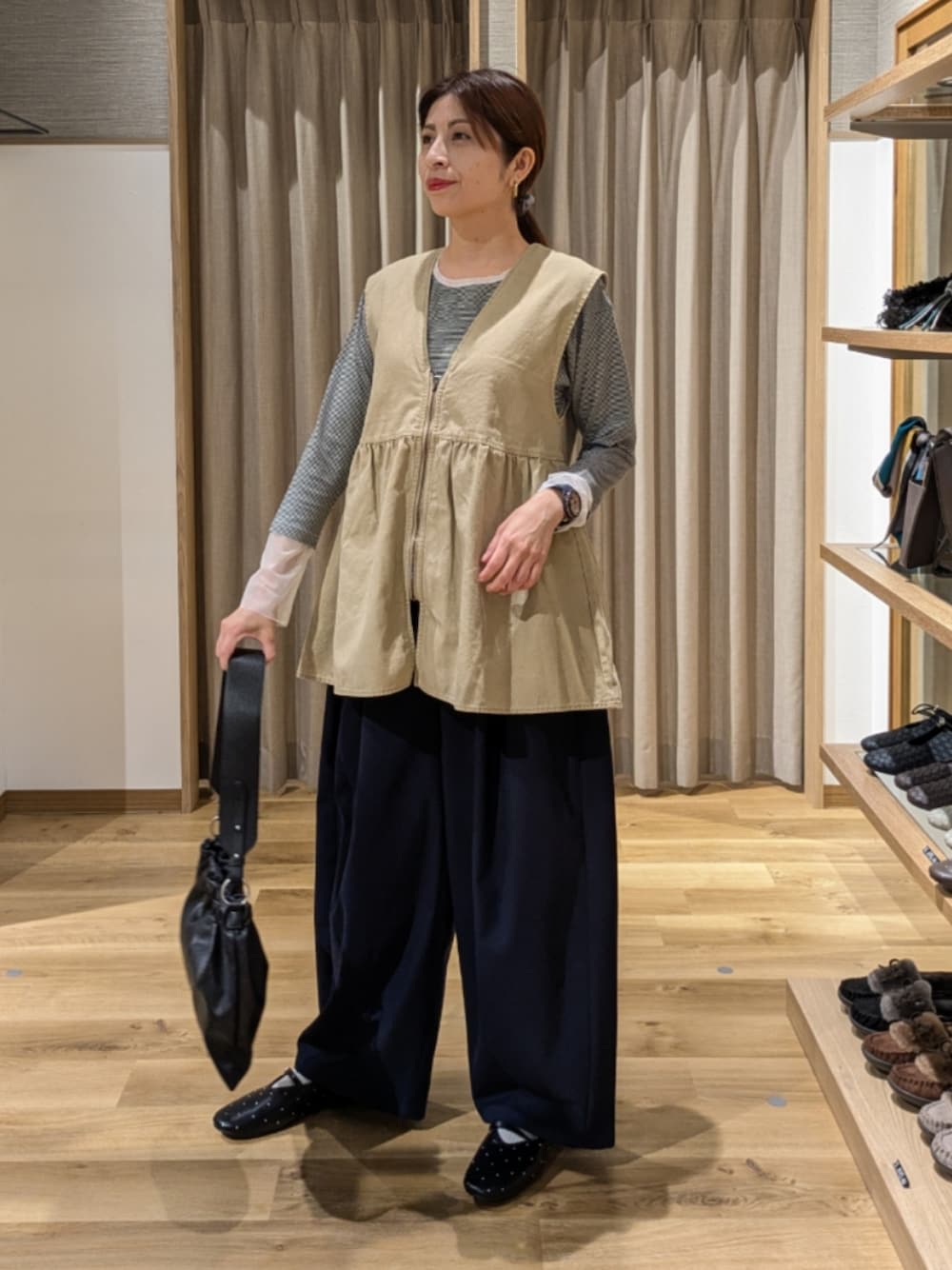 ブルー系のその他パンツ、ベージュ系のベスト、ブラック系のショルダーバッグを着用したレディースの秋コーディネートの1枚目の写真