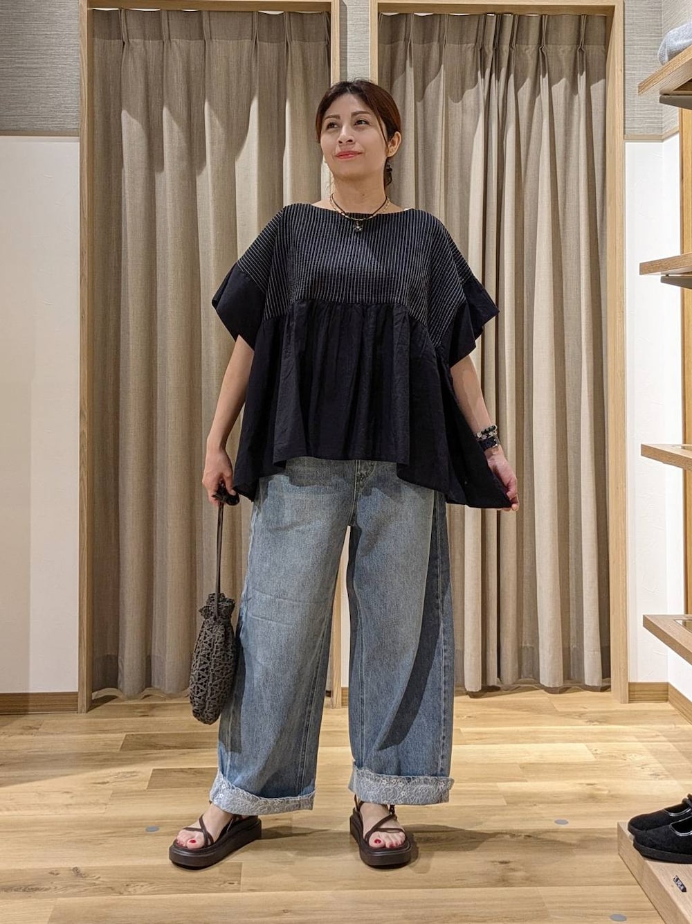 ブルー系のデニムパンツ、ブラウン系のサンダル、ブラック系のシャツ/ブラウスを着用したレディースの夏コーディネートの1枚目の写真