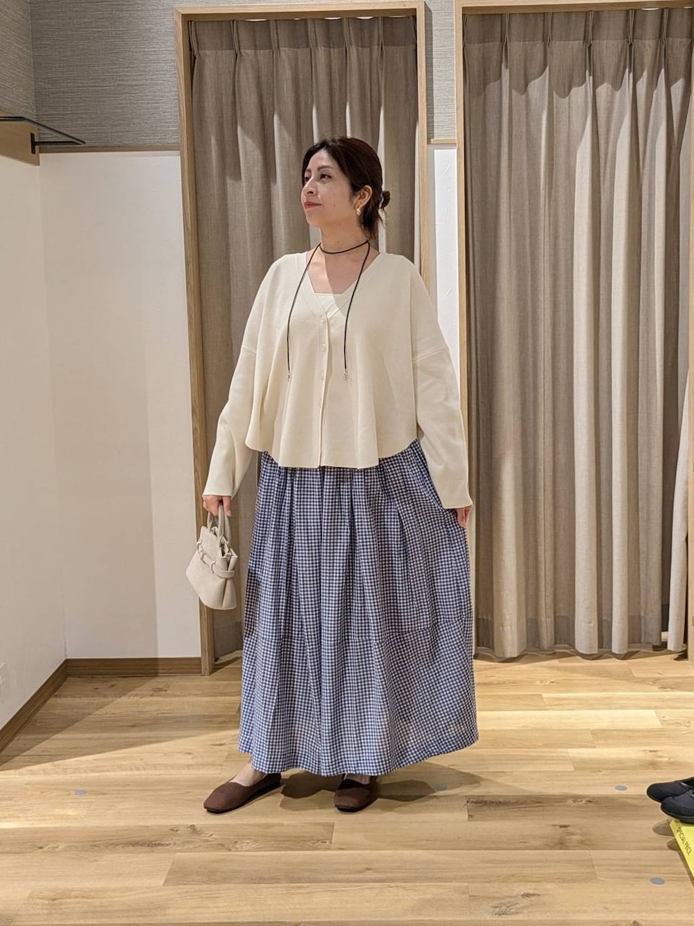ベージュ系のショルダーバッグ、ブラウン系のパンプス、ベージュ系のタンクトップを着用したレディースの春コーディネートの1枚目の写真