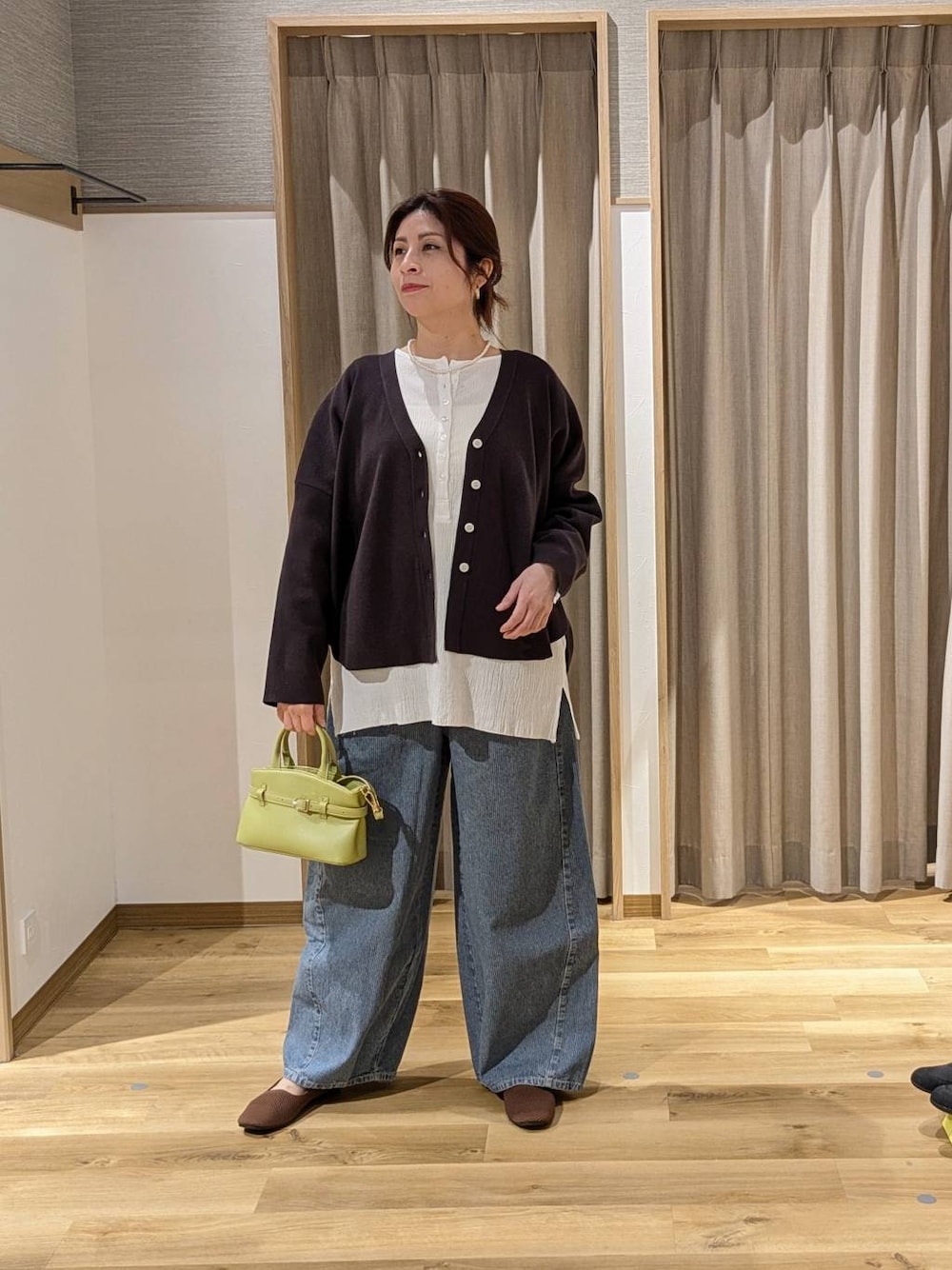 ブルー系のデニムパンツ、グレー系のカーディガン/ボレロ、グリーン系のショルダーバッグを着用したレディースの春コーディネートの1枚目の写真