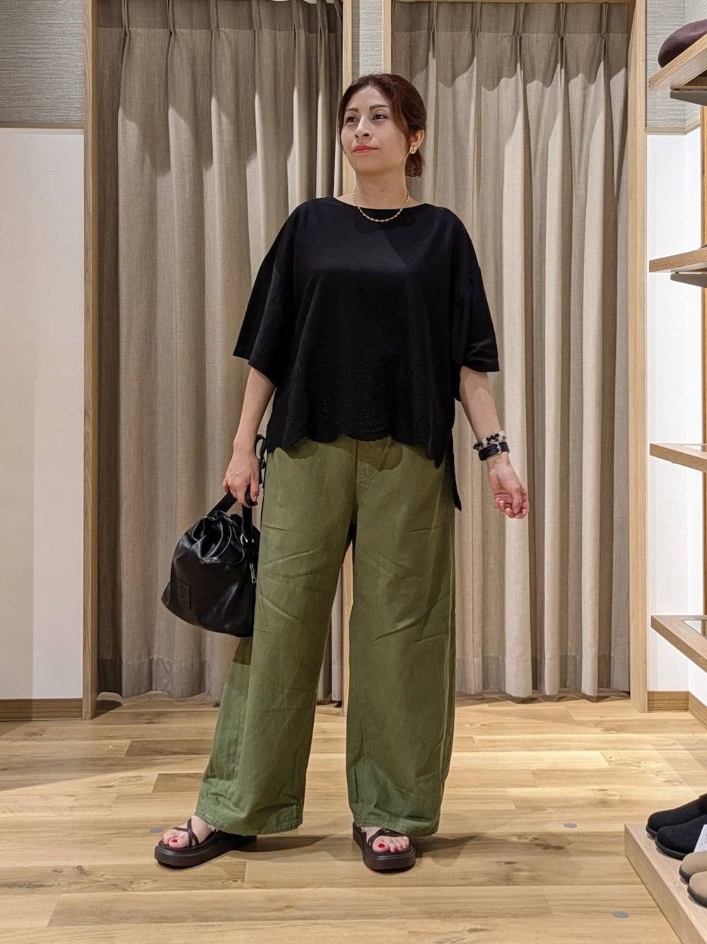 グリーン系のデニムパンツ、ブラック系のTシャツ/カットソー、ブラウン系のサンダルを着用したレディースの夏コーディネートの1枚目の写真