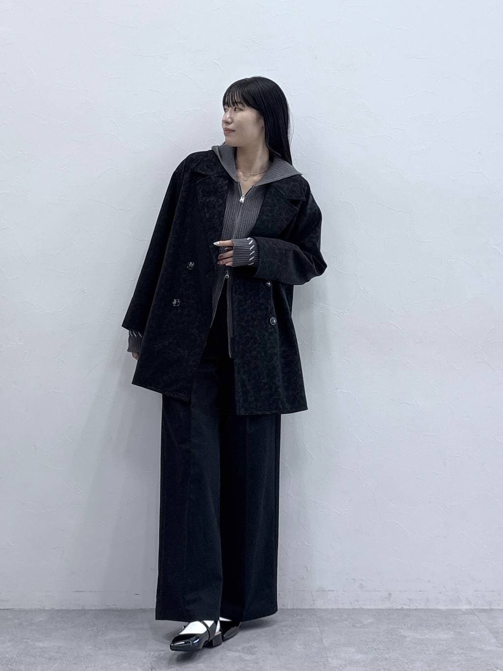 グレー系のニット/セーター、ブラック系のパンプス、ブラック系のチノパンツを着用したレディースの冬コーディネートの1枚目の写真