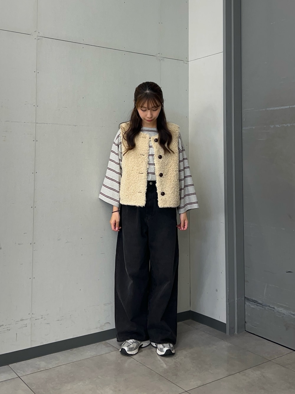 グレー系のTシャツ/カットソー、ベージュ系のダウンベスト、ブラック系のデニムパンツを着用したレディースの秋コーディネートの1枚目の写真