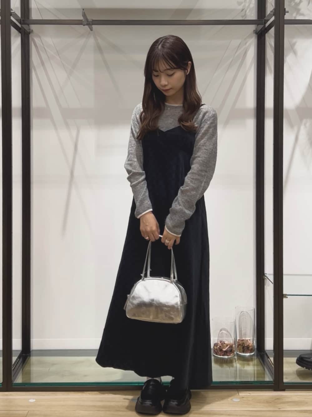 グレー系のニット/セーター、グレー系のワンピース、シルバー系のボストンバッグを着用したレディースの秋コーディネートの1枚目の写真
