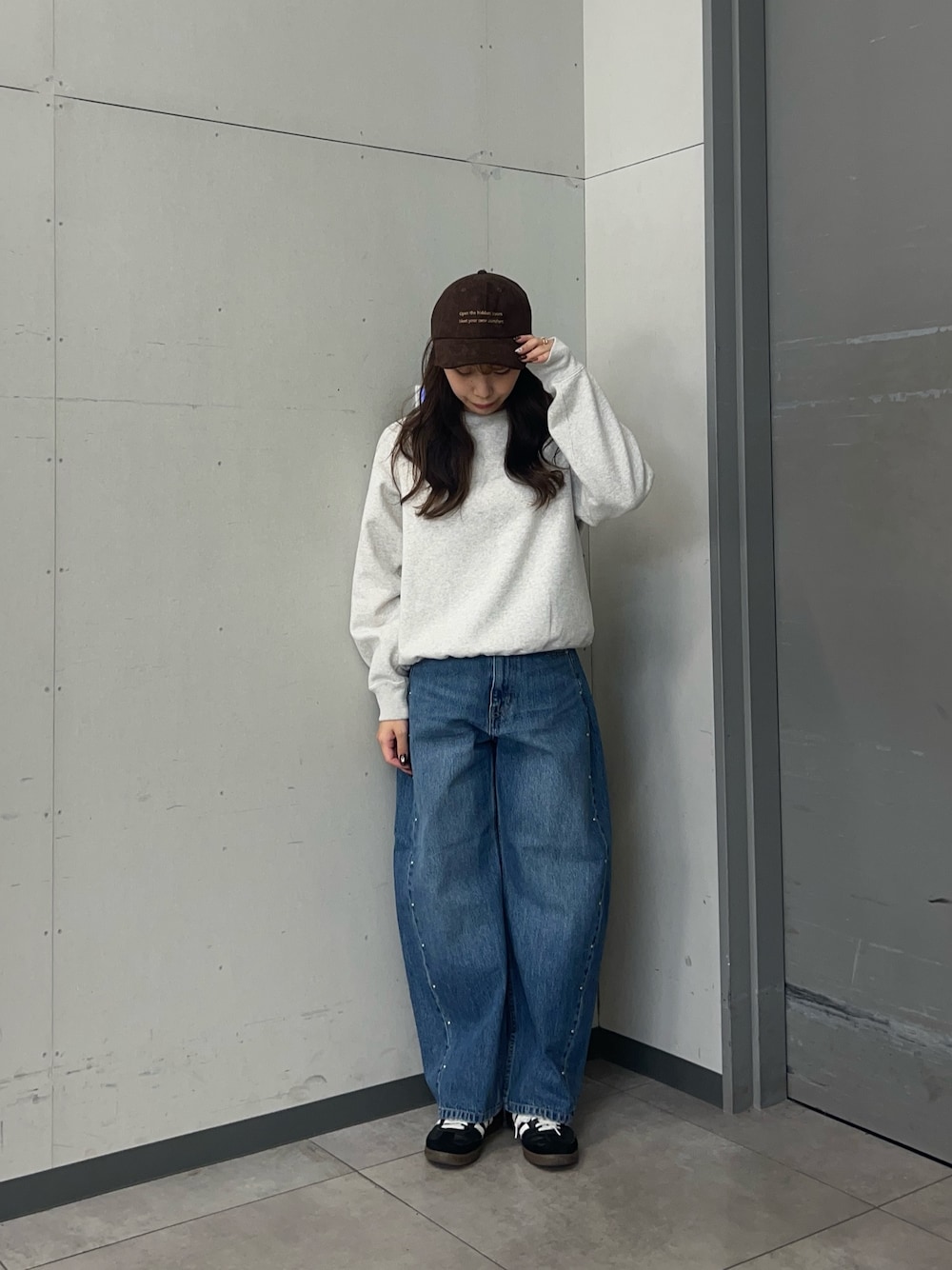 グレー系のスウェット、ブルー系のデニムパンツ、ブラック系のスニーカーを着用したレディースの秋コーディネートの1枚目の写真