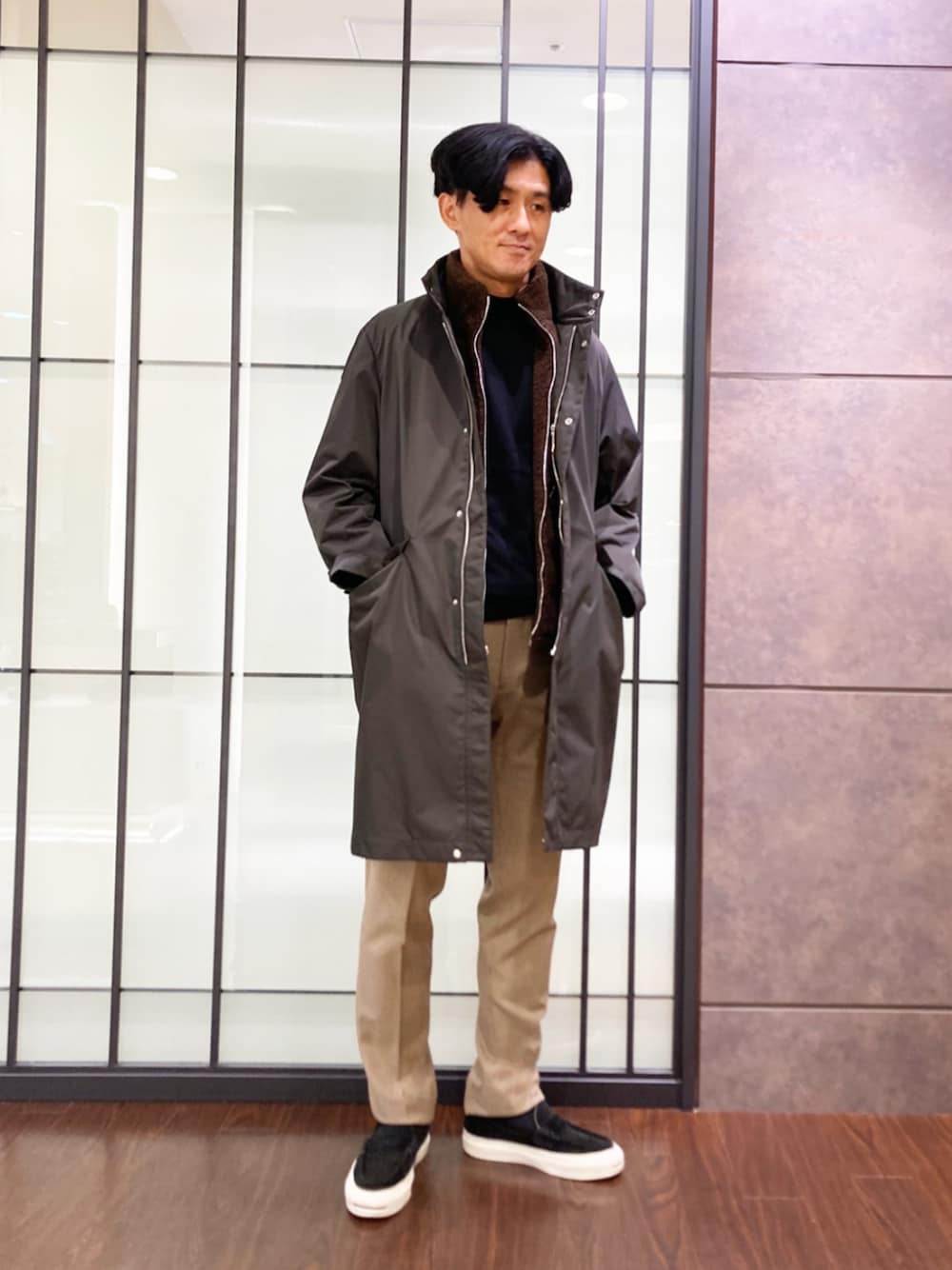 ブラック系のニット/セーター、グレー系のその他アウター、ベージュ系のその他パンツを着用したメンズの秋コーディネートの1枚目の写真