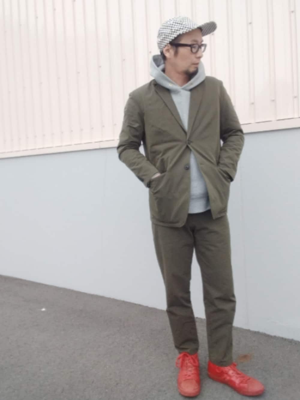 グリーン系のセットアップ、グレー系のパーカー、レッド系のスニーカーを着用したメンズの秋コーディネートの1枚目の写真