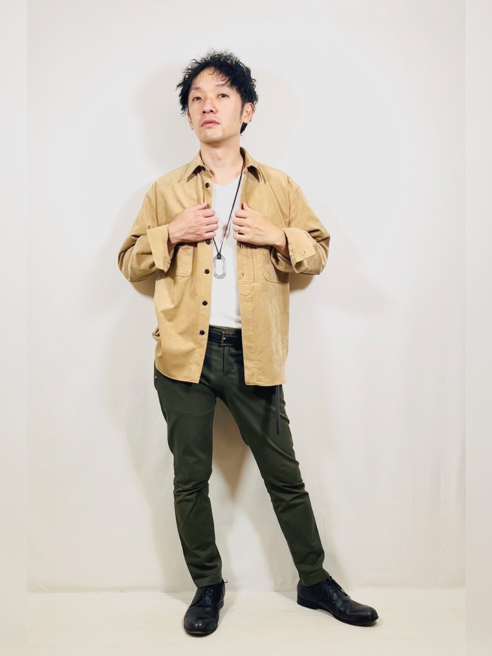 ベージュ系のシャツ/ブラウス、グリーン系のスラックス、ブラック系のドレスシューズを着用したメンズの秋コーディネートの1枚目の写真